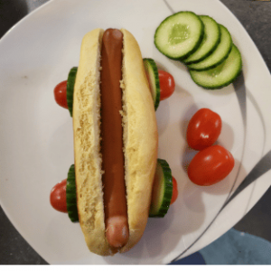 Ein Hot Dog als Rennauto gebaut mit Gurken und Tomaten als Räder